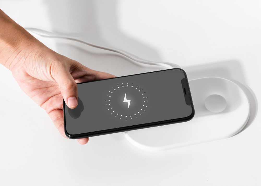 Un homme qui utilise un "chargeur sans fil" avec la "technologie MagSafe d’Apple", un exemple d'une utilisation moderne et efficace des produits Apple.